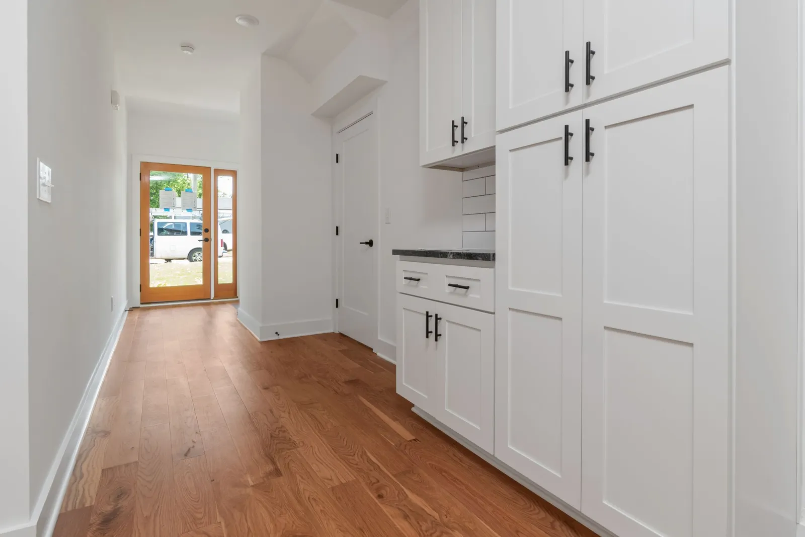 Low-sheen hardwood flooring in a bright white kitchen