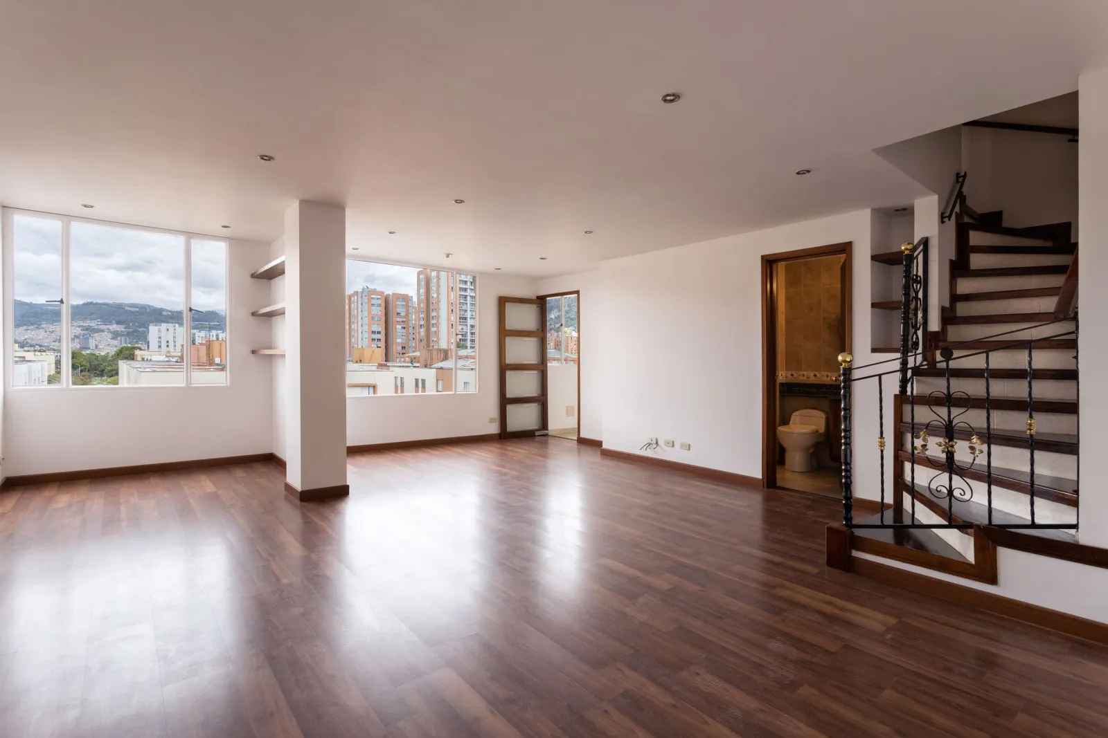 Sanded and refinished wood floor in a living room with stairs